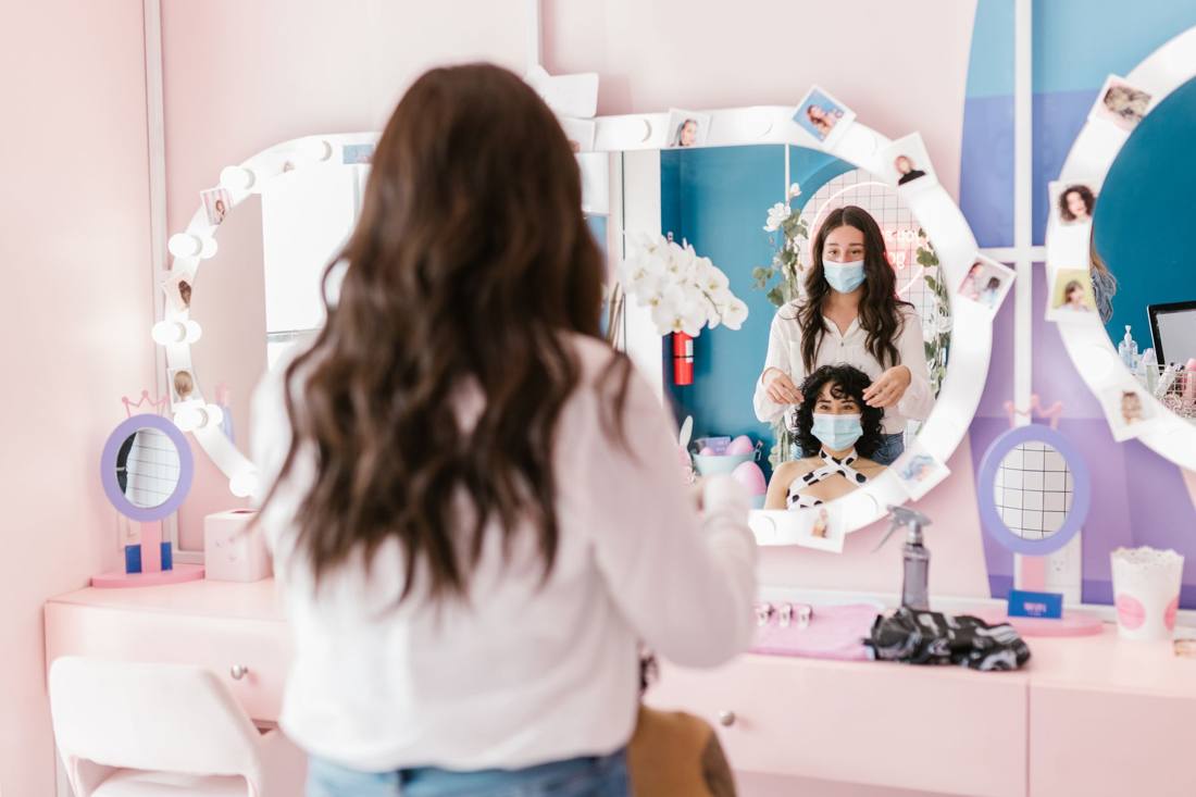 Hairdresser and client wearing masks in a modern salon, reflecting pandemic safety measures.