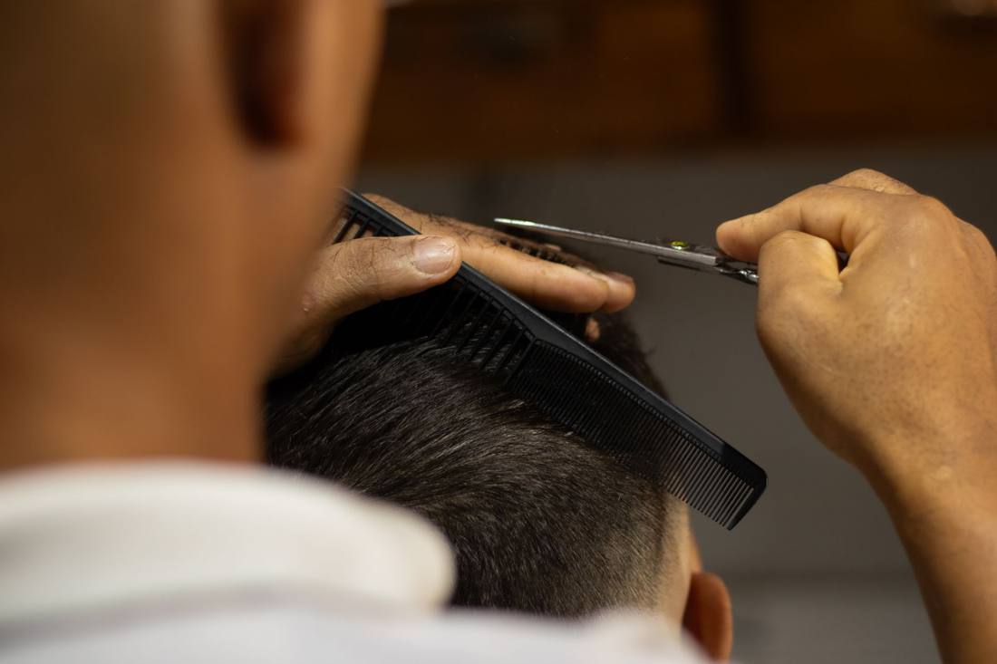 Close-up of a barber cutting hair with scissors and comb, showcasing precision and skill.